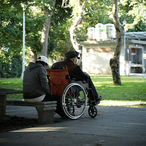 Caregiver assisting with household tasks for an elderly man in a wheelchair, promoting Supported Independent Living (SIL) under NDIS Disability Support Provider in Clyde North - Melbourne