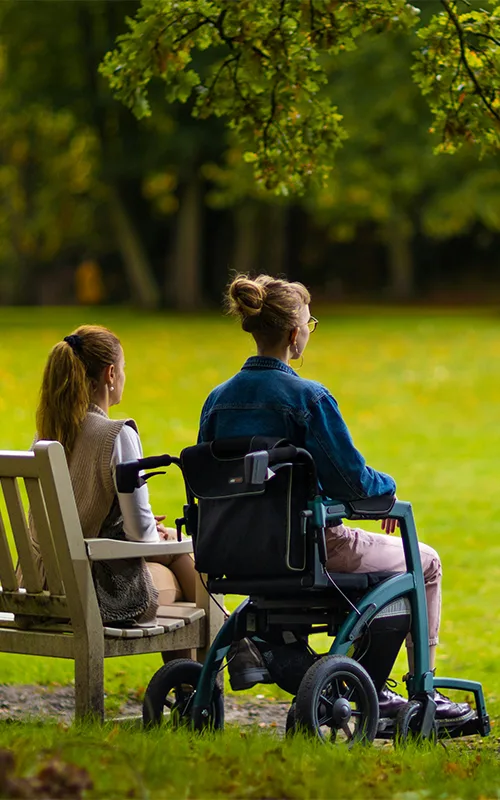 NDIS support worker sitting with a person in a wheelchair at a park in Clyde North, Melbourne
