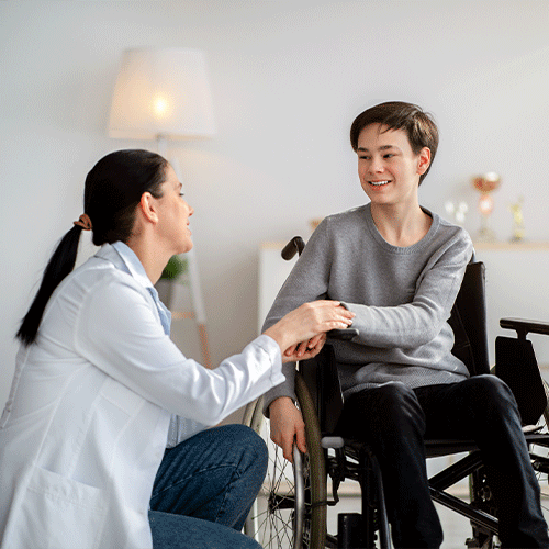 Smiling healthcare professional supporting a young person in a wheelchair during an NDIS continence assessment at home in Sunshine, Melbourne.