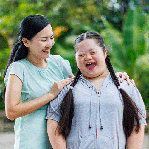 Smiling carer supporting a happy young woman outdoors, symbolising compassionate NDIS continence care and community support in Darwin, Northern Territory.
