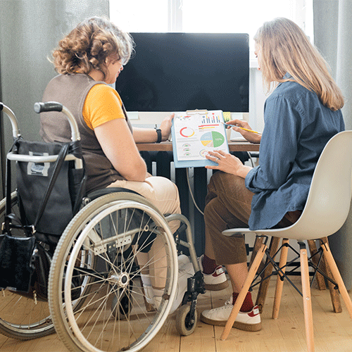 Two women reviewing documents together, including one using a wheelchair, representing continence assessment and NDIS support services in Alice Springs, Northern Territory.