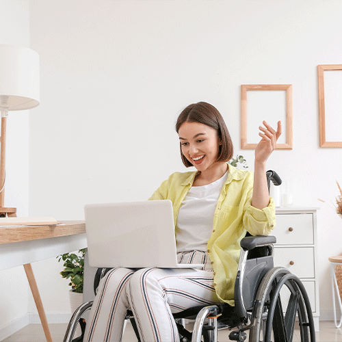 Woman in a wheelchair smiling while using a laptop, representing continence assessment and disability support services in Tasmania.
