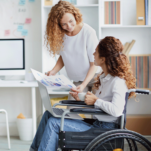 Support worker discussing care documents with a woman in a wheelchair, representing continence assessment and disability support in Canberra, ACT.