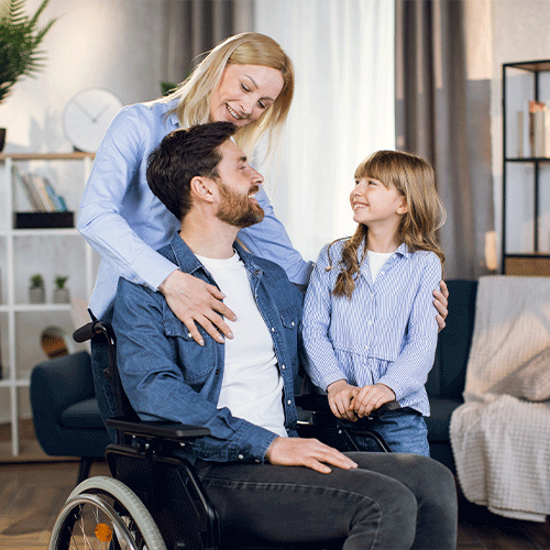Smiling family supporting a man in a wheelchair at home, representing continence and disability support services in Deer Park, Victoria.