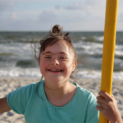 Smiling young girl enjoying time outdoors by the beach, representing inclusive disability and continence support services in Devonport, Tasmania.