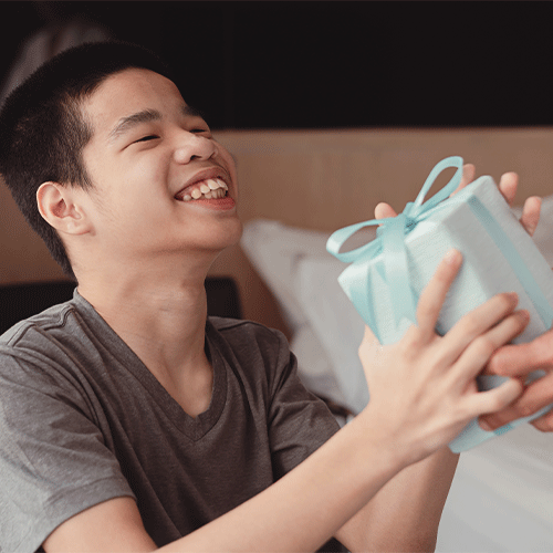 Smiling young person in a wheelchair receiving a gift, representing supportive continence and disability care in Woree, Queensland.