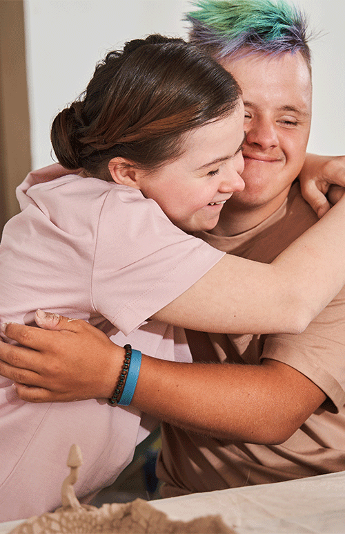 A nurse warmly embracing a young adult with Down syndrome during a telehealth continence assessment consultation in Brisbane, QLD — A1 Care Group
