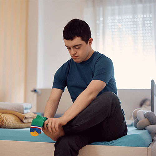 Young man with disability sitting on bed in Penrith NSW receiving NDIS continence assessment support from A1 Care Group