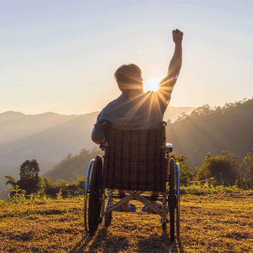 Person in wheelchair raising fist triumphantly at sunrise — continence assessment in Chirnside Park, Vic empowers NDIS participants to live independently
